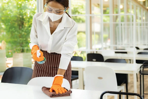 A lady cleaning a restaurant tables